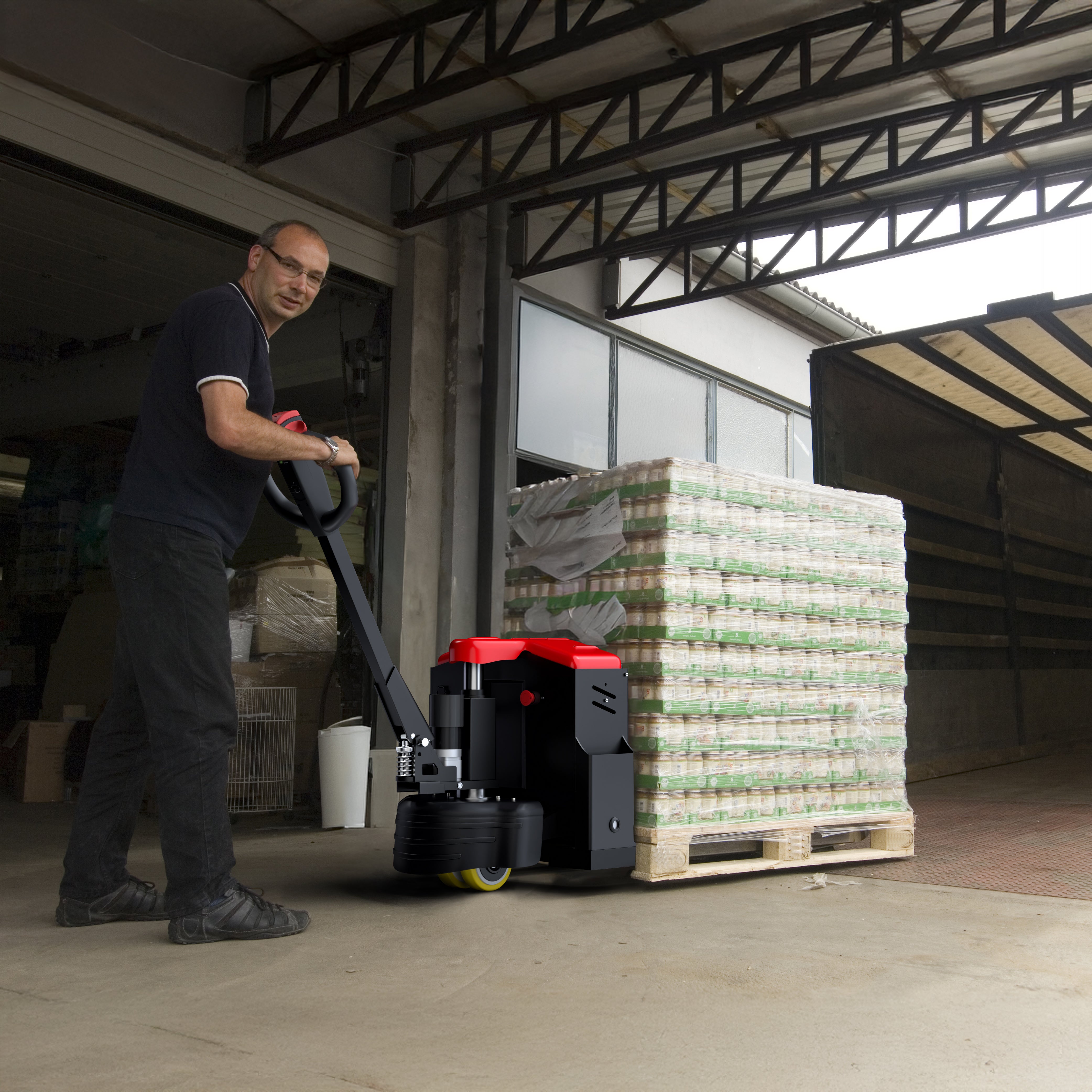 Man operating a pallet jack with stacked pallets in a warehouse setting