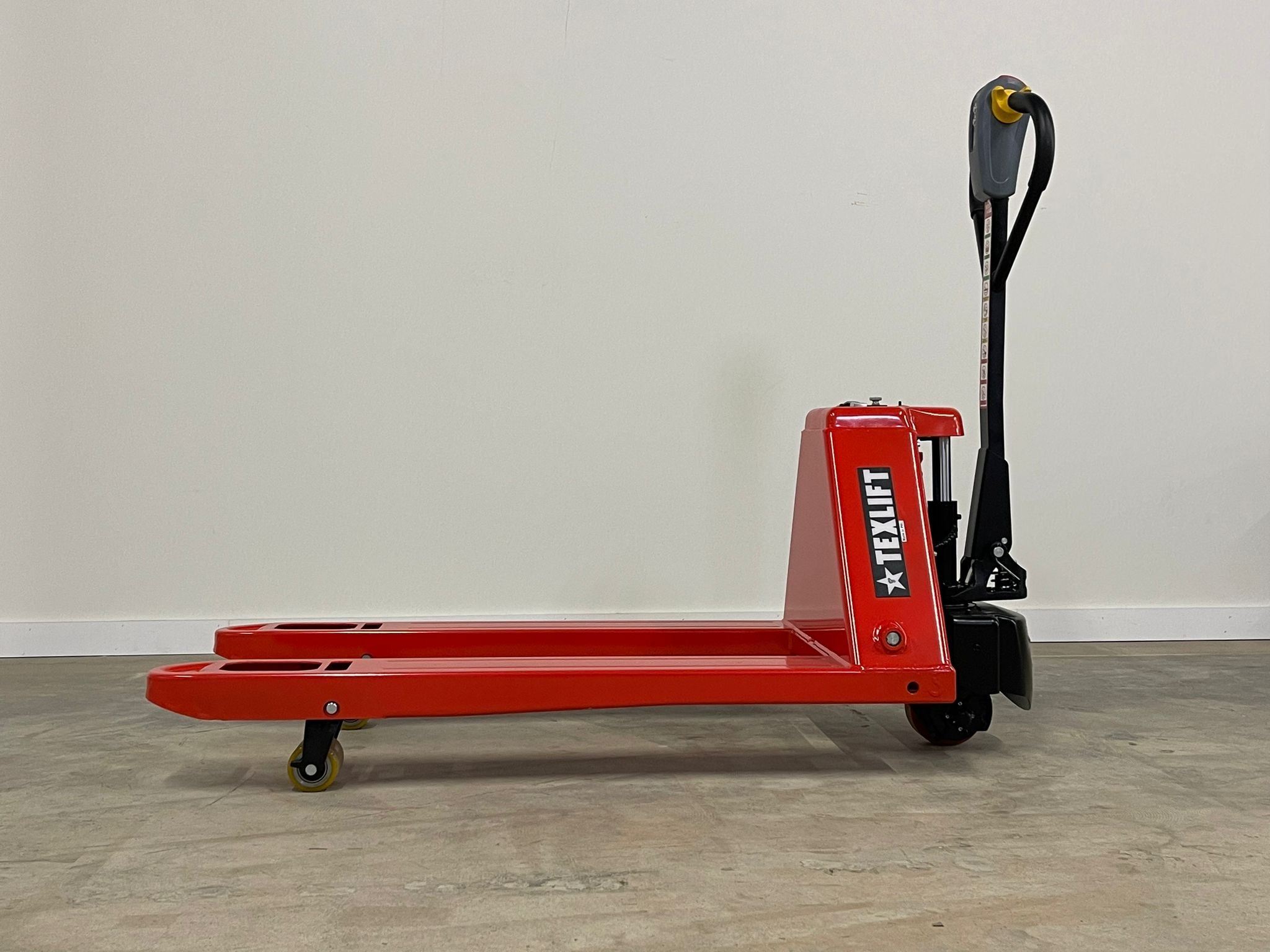 Red pallet jack with 'TEXLIFT' branding on a wooden floor against a white wall.