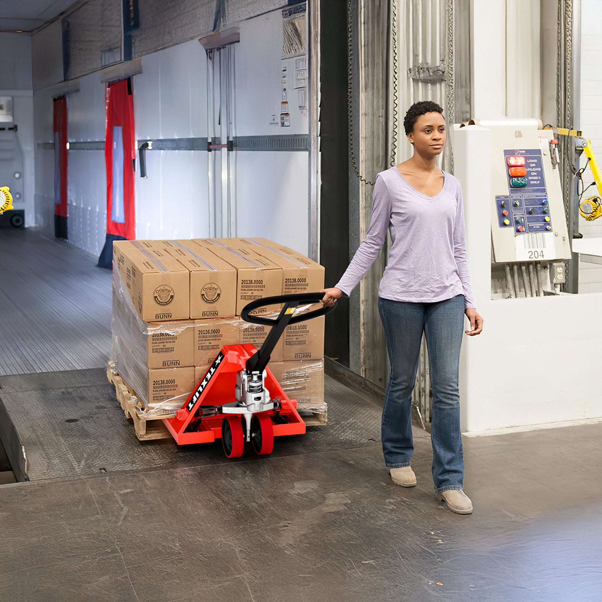 Person using a pallet jack in a warehouse setting with stacked boxes.