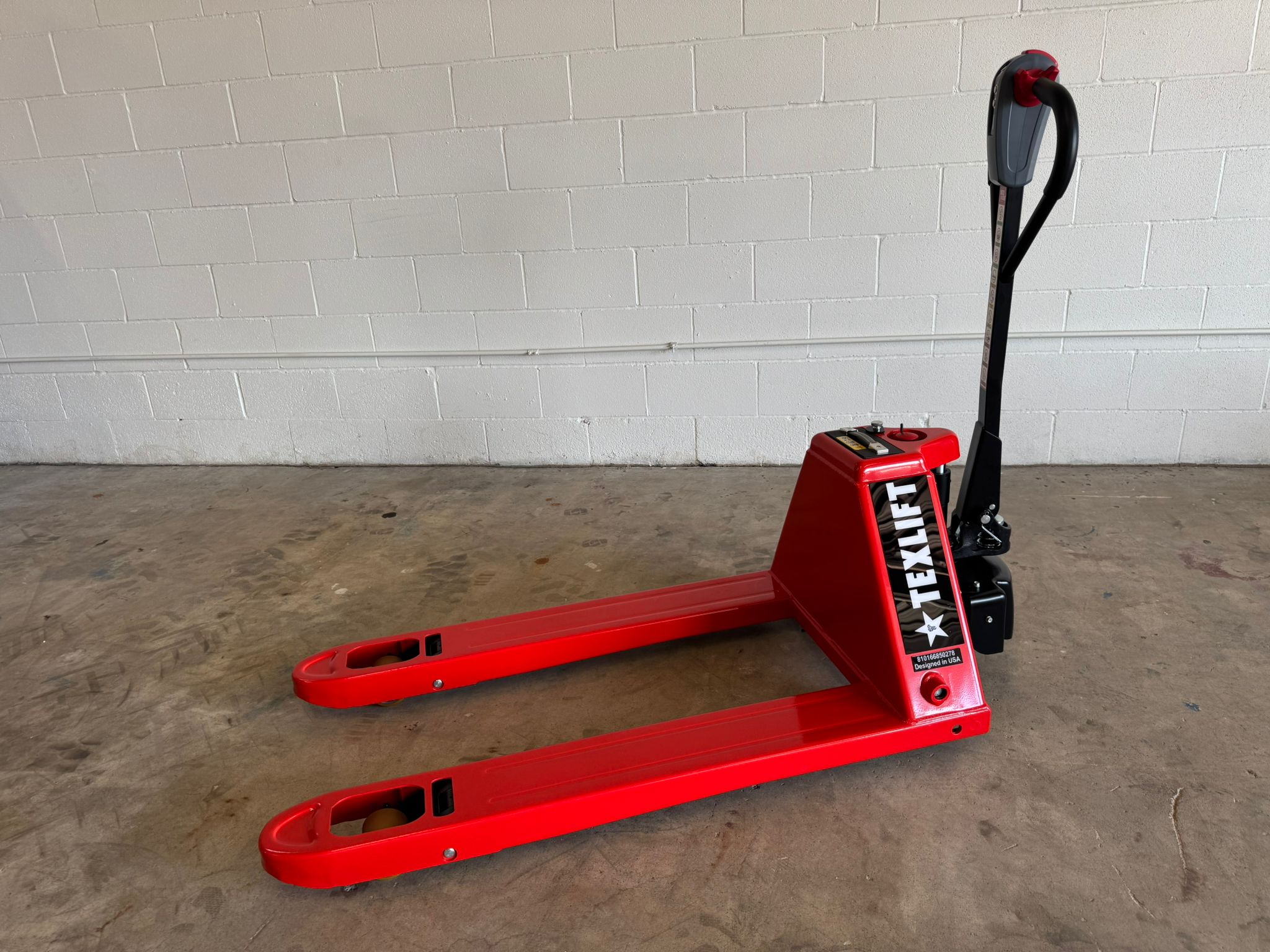 Red pallet jack with 'TEXLIFT' branding on a concrete floor against a white brick wall.